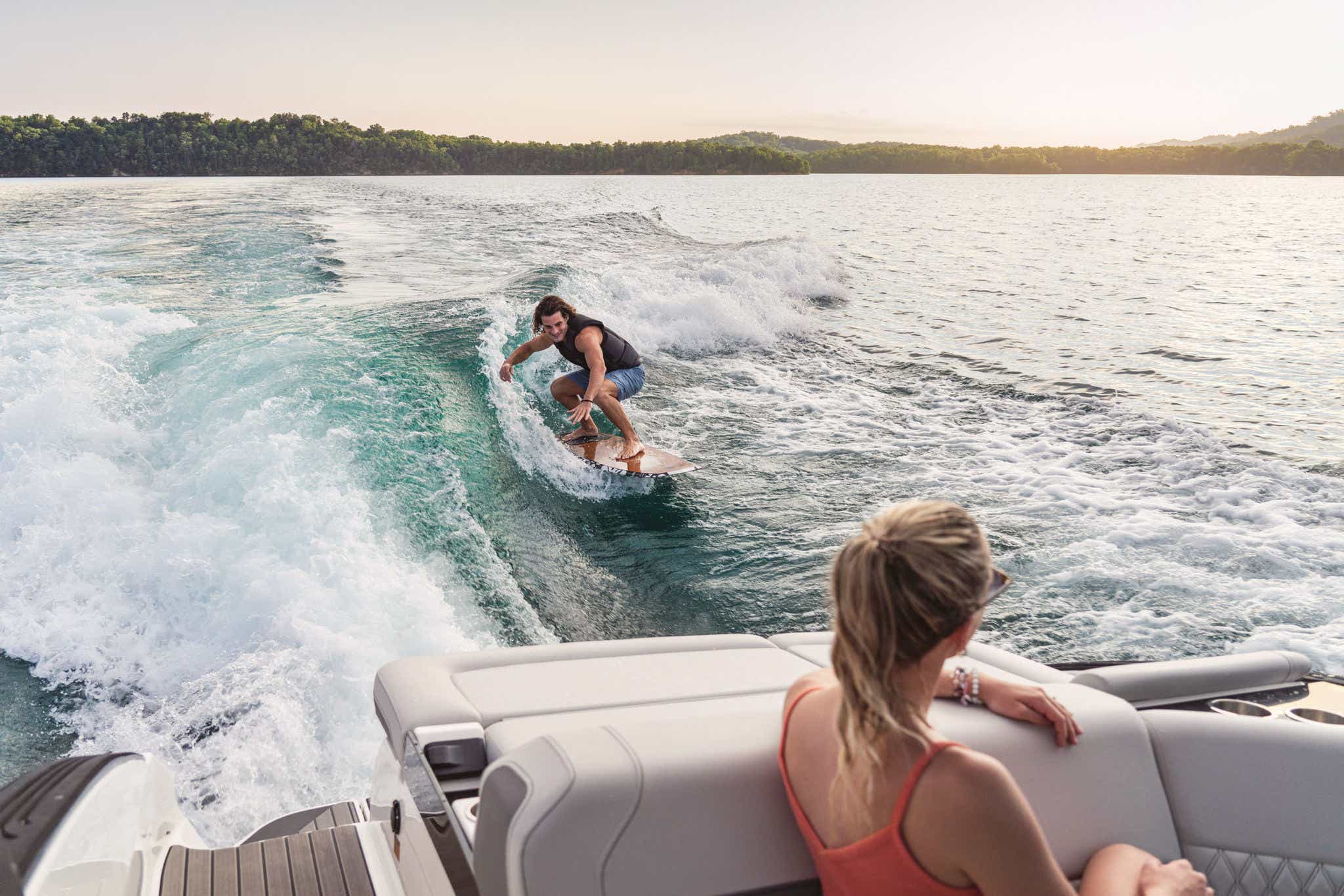 Couple wakesurfing behind the SLX 260 Surf in life jackets
