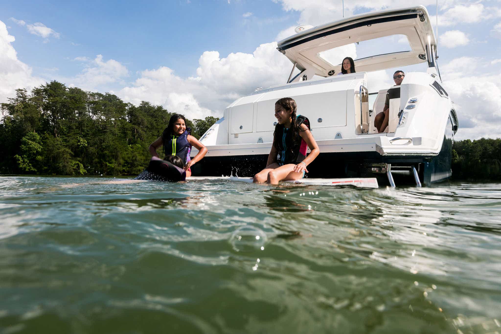 Family swimming off the swim platform of a Sundancer 320