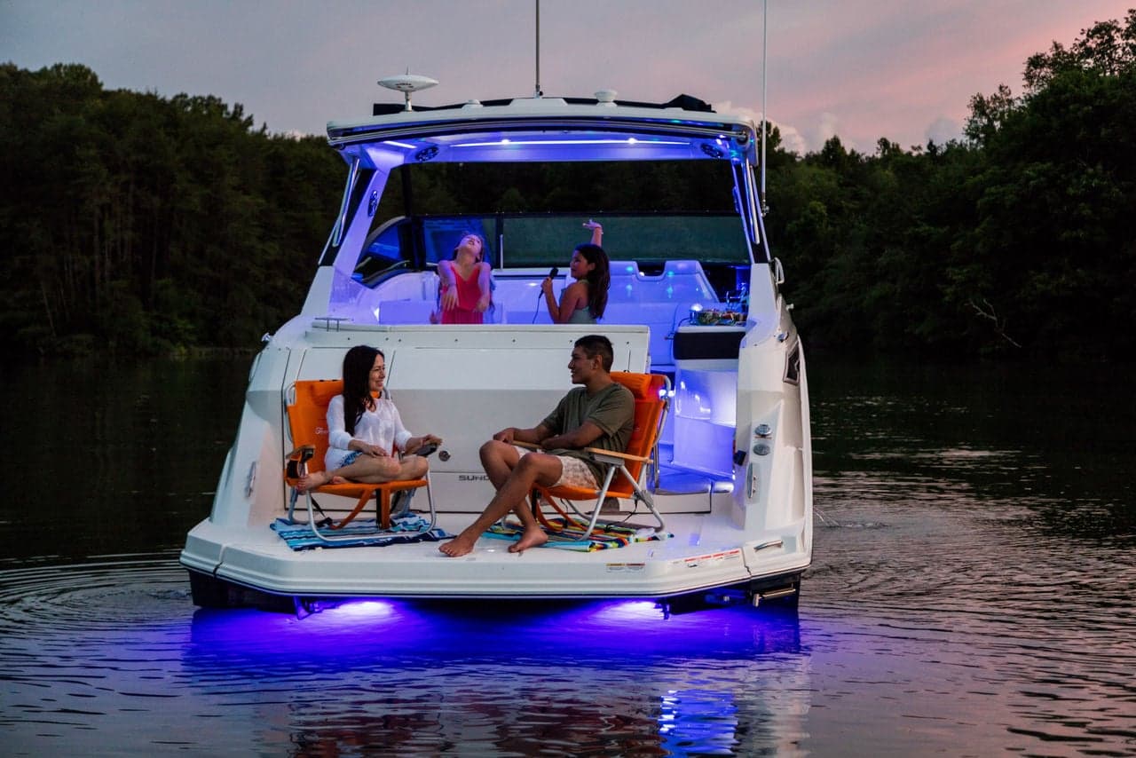 Sundancer 320 family enjoying karaoke at the swim platform under accent lighting